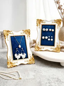 Detalle de marcos de exhibición de joyas vintage blancos y dorados con terciopelo azul.