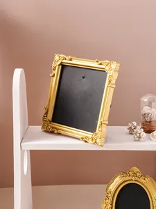 Detailed view of an ornate vintage golden relief photo frame set on a minimalist white shelf