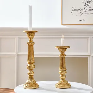 Primer plano de candelabros tallados en oro vintage sobre mesa blanca elegante