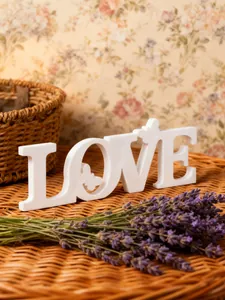 Close up view of white wooden LOVE ornament detail with butterfly cutout for table.