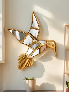 Détail d'un colibri mural en résine dorée avec incrustations de verre miroir à facettes.