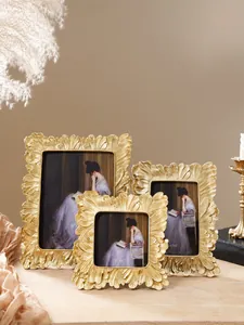 Ein detailliertes Set aus drei goldenen Fotorahmen im Vintage-Stil auf Holz