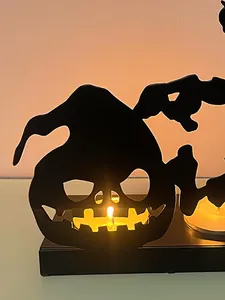 Close-up of black iron Halloween pumpkin candle holder with warm glowing tea light