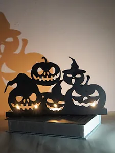 Macro view of Halloween silhouette candle holder with lit pumpkins.