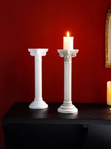 Vista detallada de candelabros retro de resina con columna romana y fondo rojo