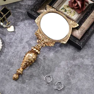 Detail of a vintage gold fox-shaped resin hand mirror with ornate floral relief