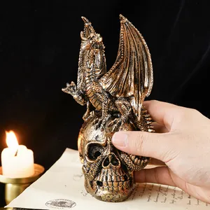 Gothic bronze dragon perched on human skull figurine shown with hand for scale