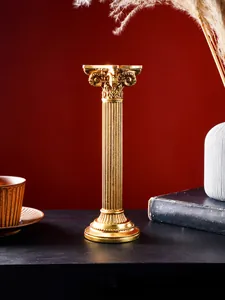 Detalle de un candelabro vintage de resina dorada con forma de columna romana clásica