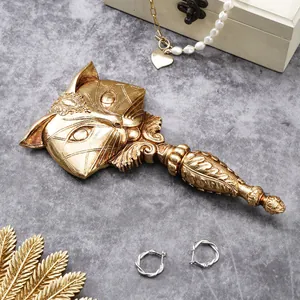 Intricate detail of a vintage golden fox-shaped resin hand mirror on a grey stone texture