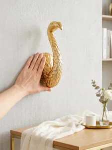 Scultura murale cigno dorato in resina con mano per scala dimensionale vista dettagli