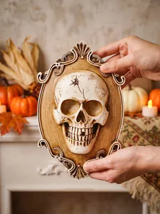 Close-up of a gothic 3D skull wall plaque featuring an ornate carved frame held by hands