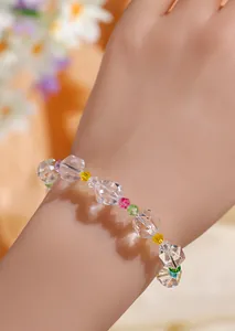 Vista detallada de una pulsera de cristal transparente facetado con cuentas de colores en la muñeca.