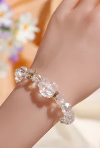 Vista detallada de una pulsera de cristal transparente facetado con detalles de corona en la muñeca