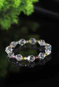 Vista de detalle de pulsera de cristal facetado con cuentas de colores sobre fondo negro.