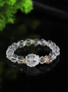 Primer plano de pulsera de cristal blanco facetado con intrincado dije de zorro
