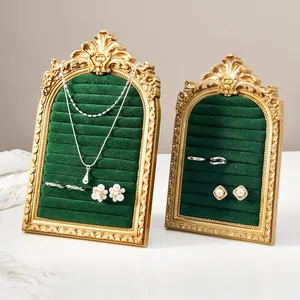 Close-up of vintage arched velvet jewelry organizers in gold ornate frames for rings and necklaces.