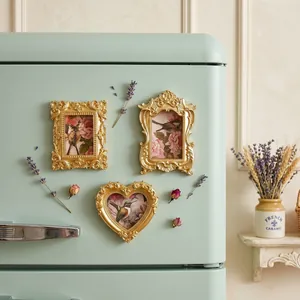 Detailed macro view of three vintage gold magnetic photo frames on a mint green fridge surface