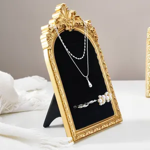 Detail view of vintage gold arched jewelry display frame with black velvet lining.