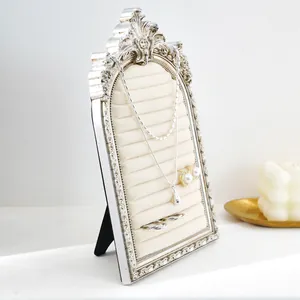 Vintage arched jewelry display stand with beige velvet slots for rings and necklaces.