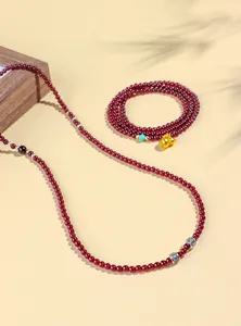 Elegante collana di perle in granato da 4mm con dettaglio ciondolo hulu dorato.