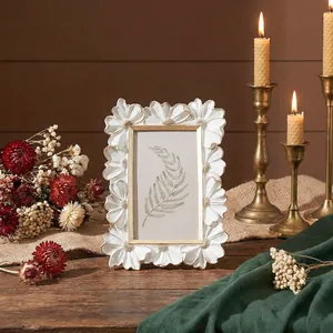 Dettaglio cornice per foto a margherita in resina bianca con candele e fiori secchi vintage
