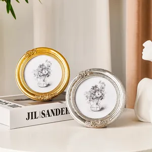 Vintage Bilderrahmen mit Rosenrelief in Gold und Silber auf weißem Tisch