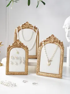 Resin photo frame jewelry display stand detail, vintage gold aesthetic setup for necklaces.
