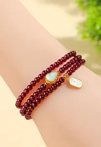 Vista macro del bracciale in granato 4mm con zucca di giada e ciondolo della pace