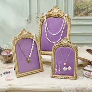 Detail view of vintage arched jewelry stands with purple velvet pads and gold frames