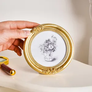 Detailansicht eines antiken goldenen runden Fotorahmens mit geprägten Rosenakzenten.
