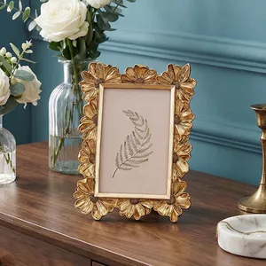Detailansicht eines goldenen Vintage-Gänseblümchen-Fotorahmens mit botanischem Farn-Druck