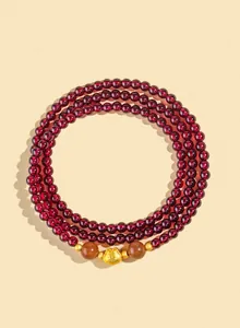 Dettaglio di un braccialetto a tre giri in granato rosso da 4mm con ciondolo portafortuna