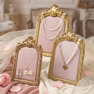 Detail of retro golden jewelry display frames with pink velvet lining and ornate carvings.