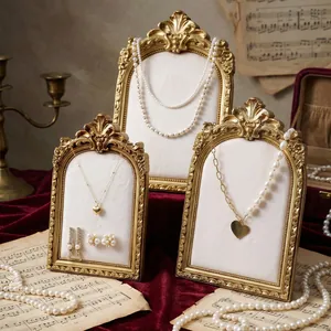 Elegant vintage golden jewelry display stands set with white velvet on red background.