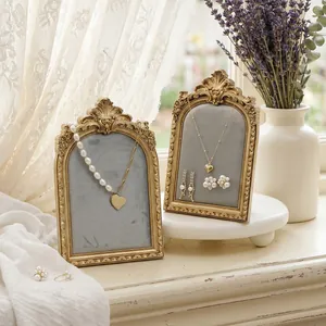 Vintage gold picture frame jewelry displays with pearl necklaces and earrings on windowsill.