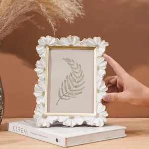 Primo piano di elegante cornice in resina bianca con margherite a rilievo e oro