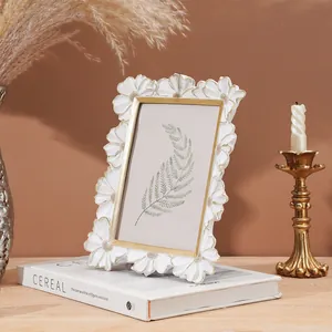 Primo piano della cornice in resina bianca con bordi dorati e motivi a margherita sbalzati