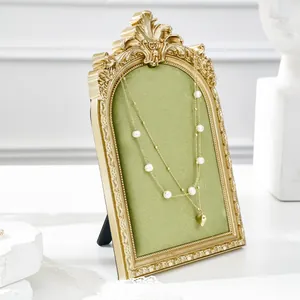 Close-up detail of vintage gold jewelry display stand featuring green velvet background