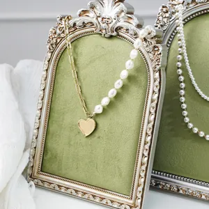 Detailed view of a vintage style ornate frame jewelry display stand with olive green velvet