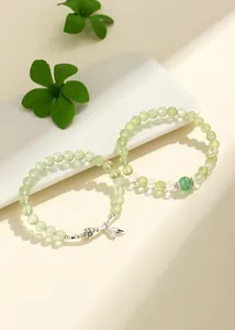 Detailed view of prehnite and green strawberry quartz beaded bracelets with charms.