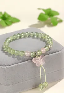 Close-up detail of the carved rose quartz butterfly pendant on the prehnite beaded bracelet.