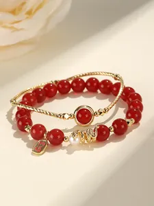 Detailed view of red agate beads, freshwater pearl, and gold-tone charms on bracelet