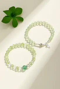 Macro view of prehnite and green strawberry quartz beaded bracelets with silver charms.
