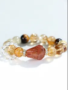 Detalle macro de una pulsera de cristal amarillo natural con piedra rojiza tallada.