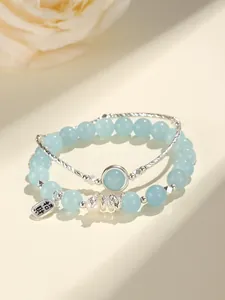 Close-up of aquamarine beaded bracelet with freshwater pearl and silver lucky charm
