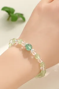 Close-up detail of a prehnite and clear crystal beaded bracelet worn on a female wrist