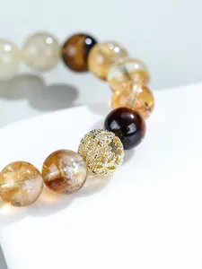 Primer plano de una cuenta hueca dorada en una pulsera de cristal amarillo