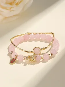 Macro detail of pink rose quartz beaded bracelet with gold snake charm and pearl