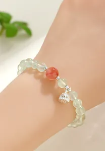 Close-up of a prehnite and rose quartz beaded bracelet with a silver lotus charm.