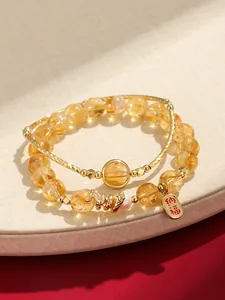 Close-up detail of yellow citrine beaded bracelet featuring a gold dragon and lucky charm tag